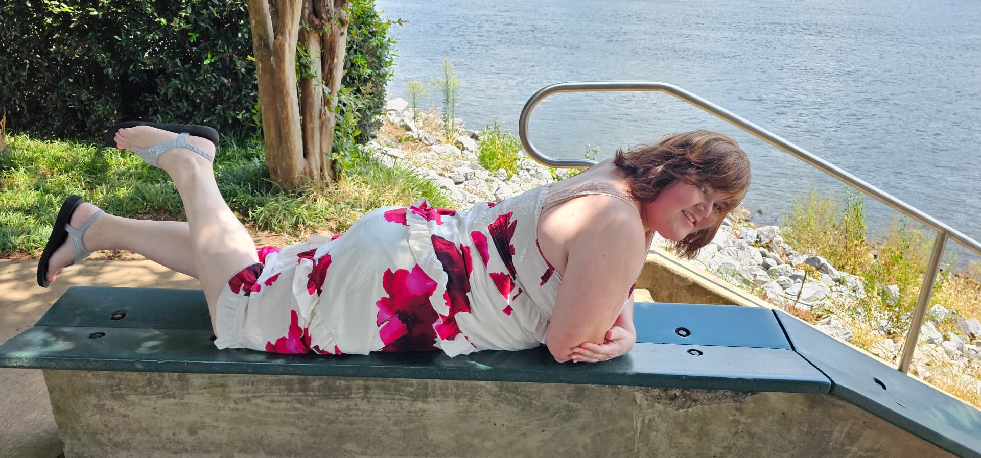 Myra posing playfully on a riverside bench