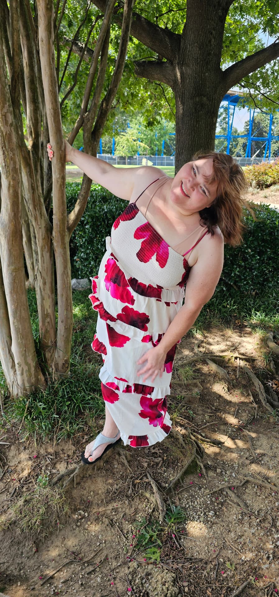 Myra laughing with the wind in her hair beside a tree