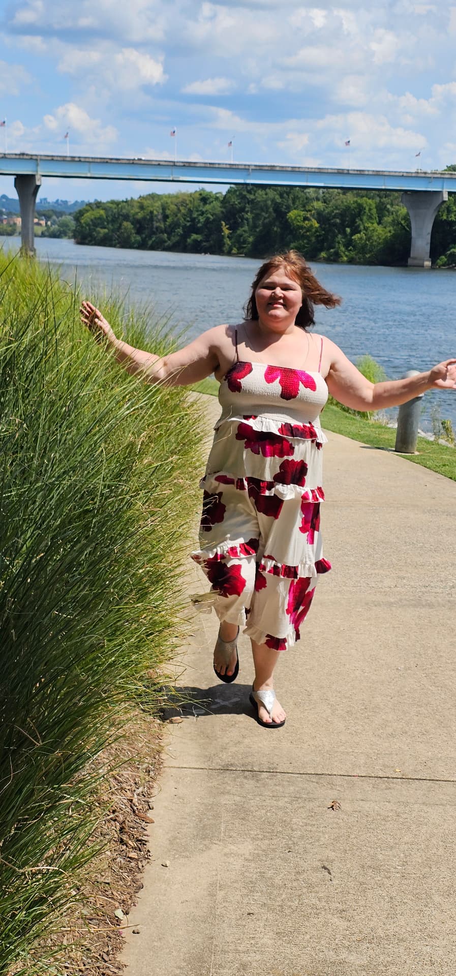 Myra walking the riverside path with her arms open