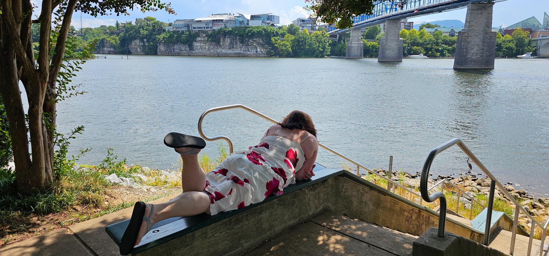 Myra resting on a bench looking out at the river
